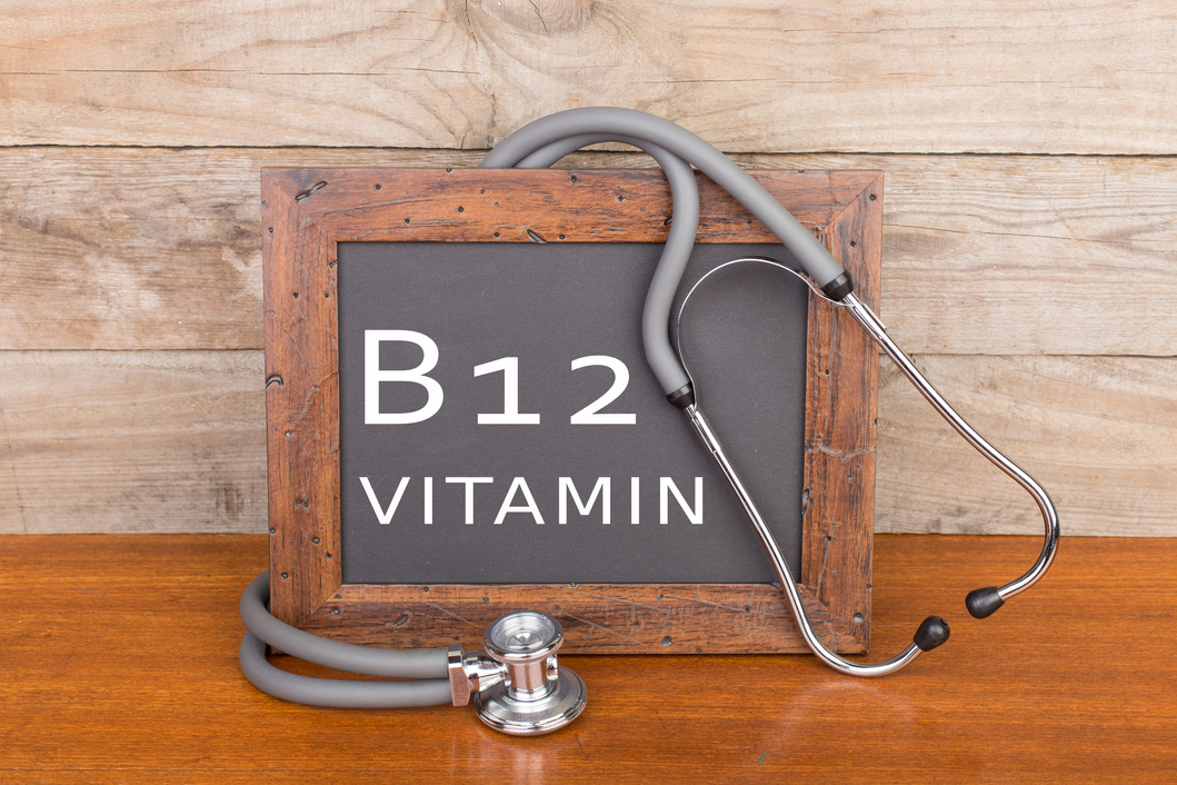 stethoscope and blackboard with text "Vitamin B12" on wooden background